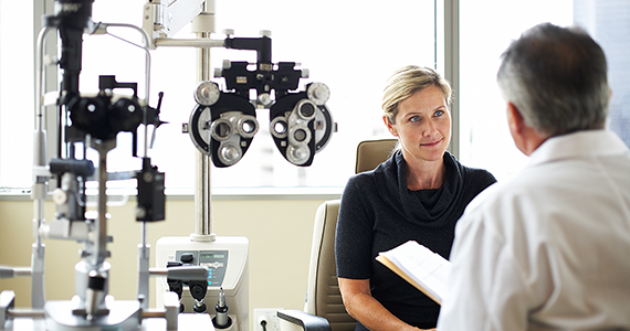 An optometrist consults with his patient in the examination room after completing her vision test